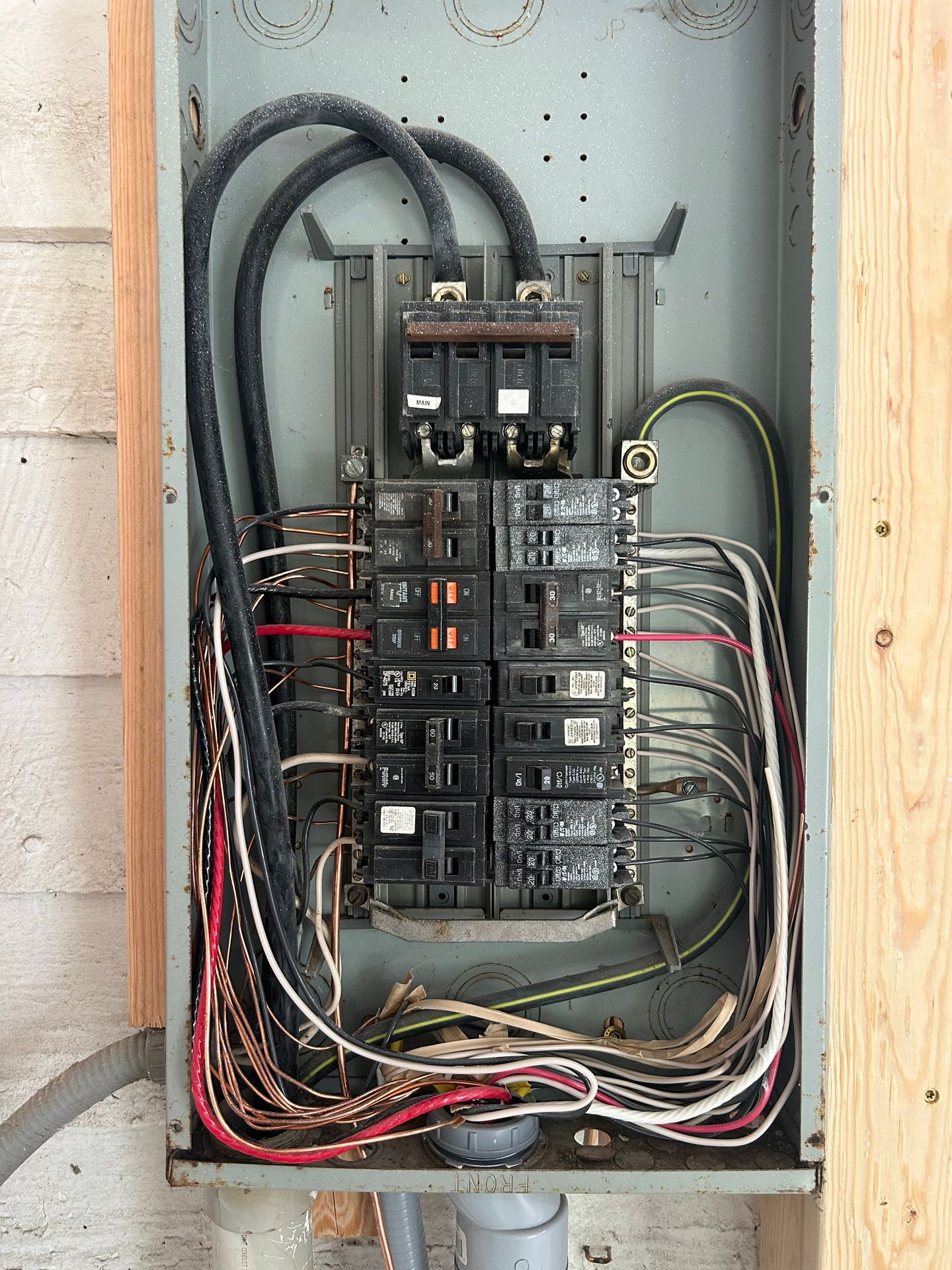 Interior view of an electrical panel with various circuit breakers and numerous cables arranged inside.