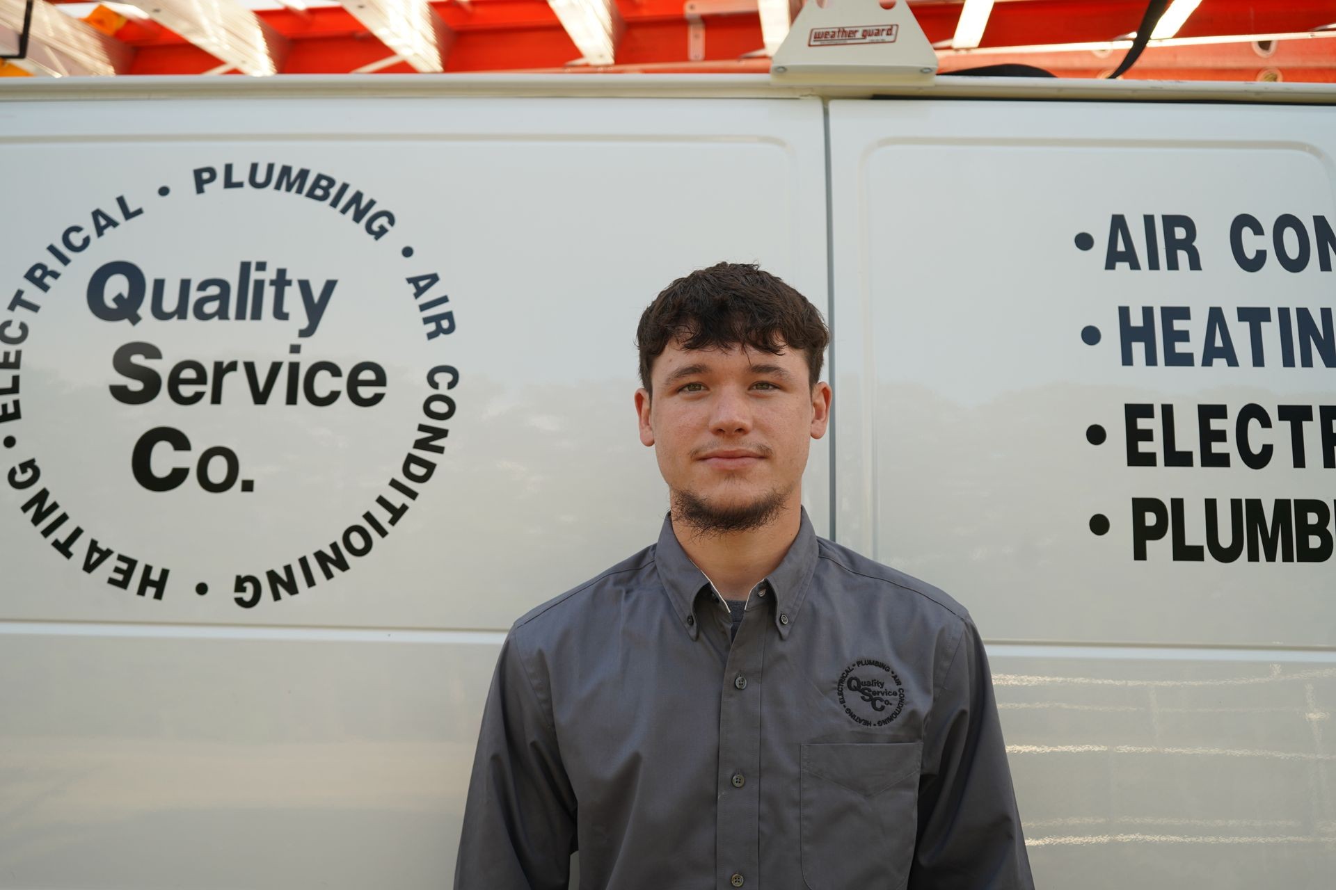 Individual in uniform standing in front of a company service van with technical service listings.
