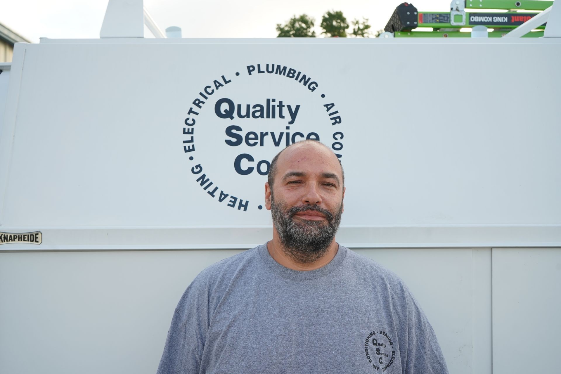 Man standing in front of a company truck with plumbing and electrical services logo.