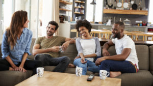 Couple Sitting On Sofa With Friends At Home Talking.