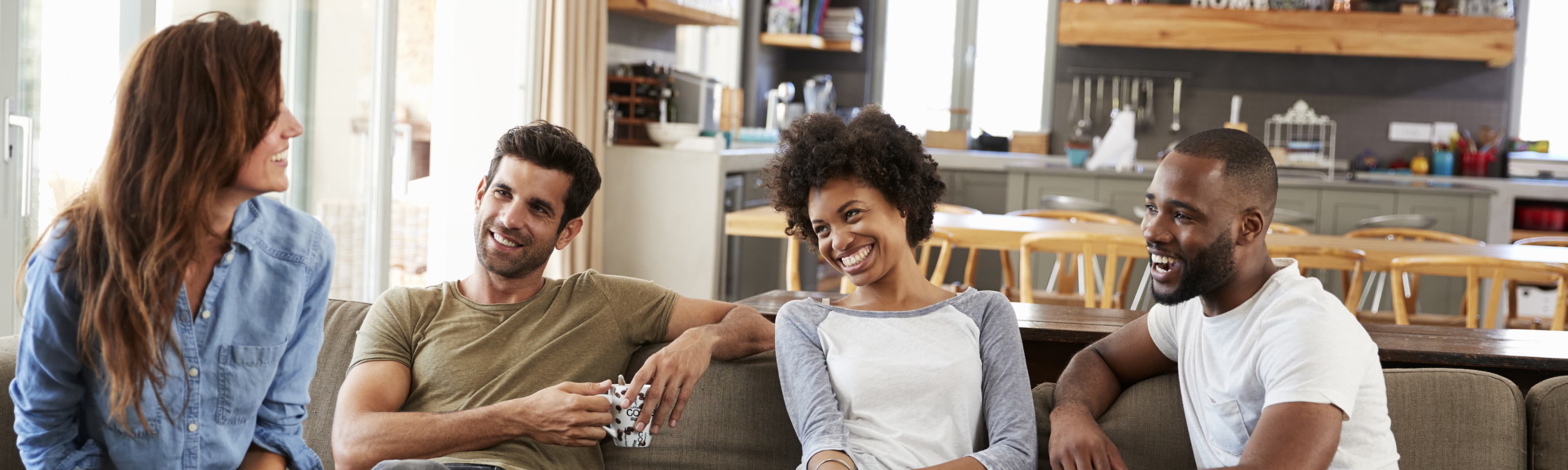 Couple Sitting On Sofa With Friends At Home Talking.