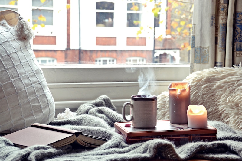 Cozy home. Candles, book and cup of tea