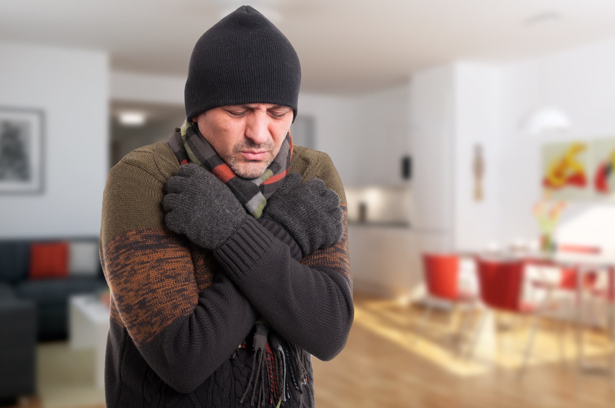 Portrait of sick man shivering from cold inside the house with copy text space