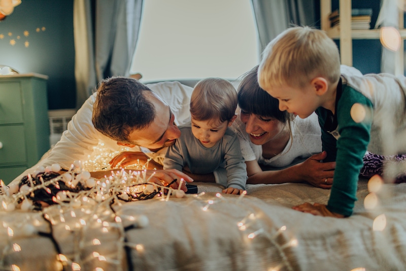 Photo of a young family with two children, enjoying together Holiday season and winter magic in their home