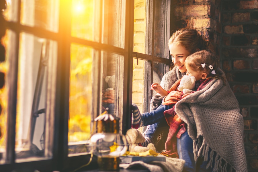 Mother and child enjoying home's heating system during fall weather after scheduling their furnace clean and check appointment