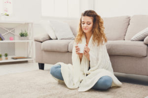 Woman trying to stay warm inside home and wondering if it's time to buy a new furnace for her home.