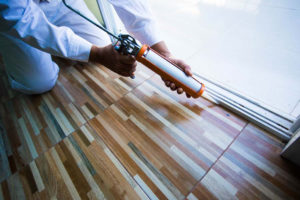 Technician making sure a window is sealed properly as part of the heat gain prevention tips we provided for your home.