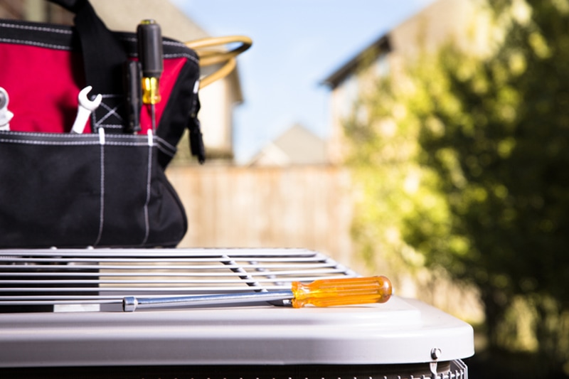 Screwdriver laying on top of an outdoor Ac unit