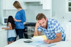 Blog Title: Why Is My Heat Pump Turning On and Off Frequently? Photo: Worried father looking at bills at home