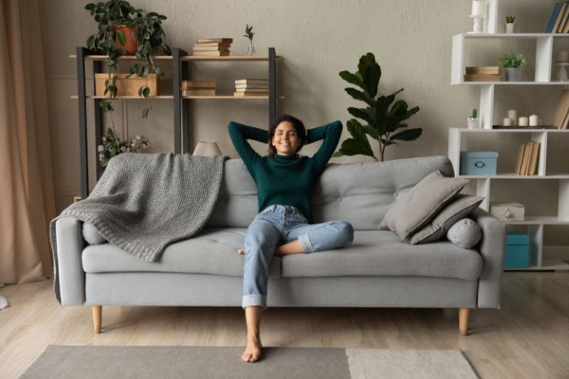 Blog Title: How a Whole-House Humidifier Keeps You Healthy Photo: Woman relaxing on a coach in her living room