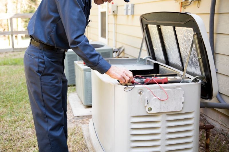 How to Maintain Your Whole-House Generator - Man Opening up a Generator and Repairing it.