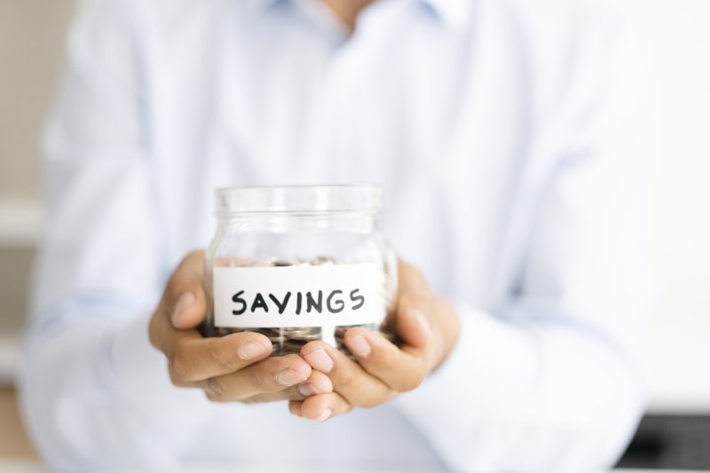 Why Buying a Heat Pump Instead of a Furnace Makes Sense. Businessman holding jar of savings.